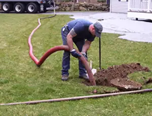 Septic pumping technician servicing a residential septic tank with a vacuum hose in Nashville, TN