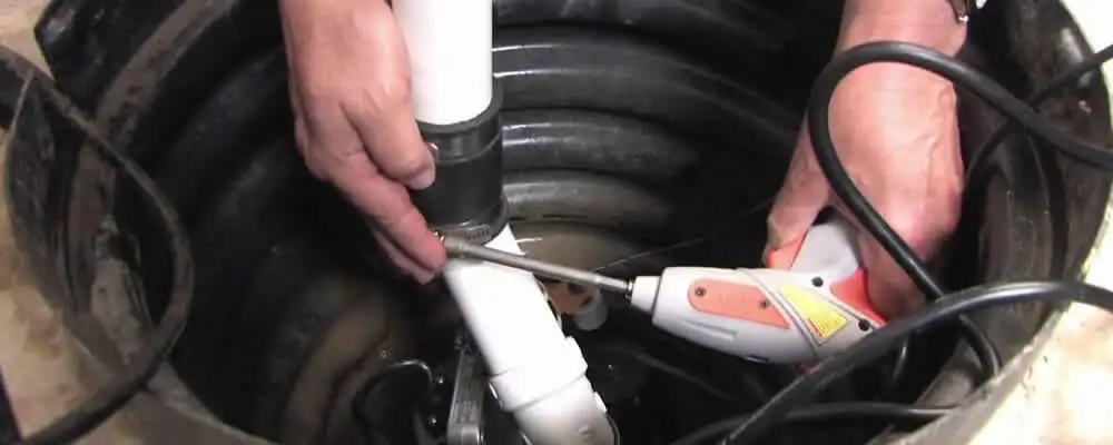 Sump pump installation technician connecting PVC discharge piping in Nashville, TN