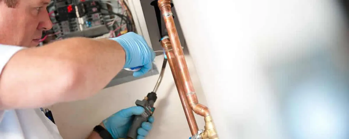 Water heater repair technician testing copper pipe connections and controls in Nashville, TN