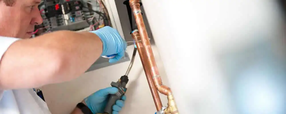 Water heater repair technician testing copper pipe connections and controls in Nashville, TN
